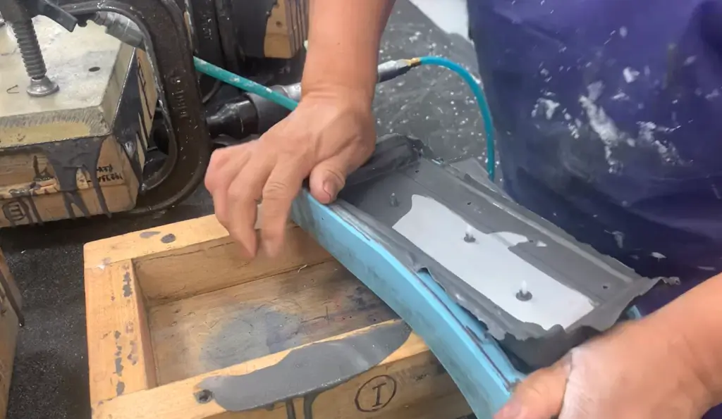 Hands molding clay in a wooden frame.